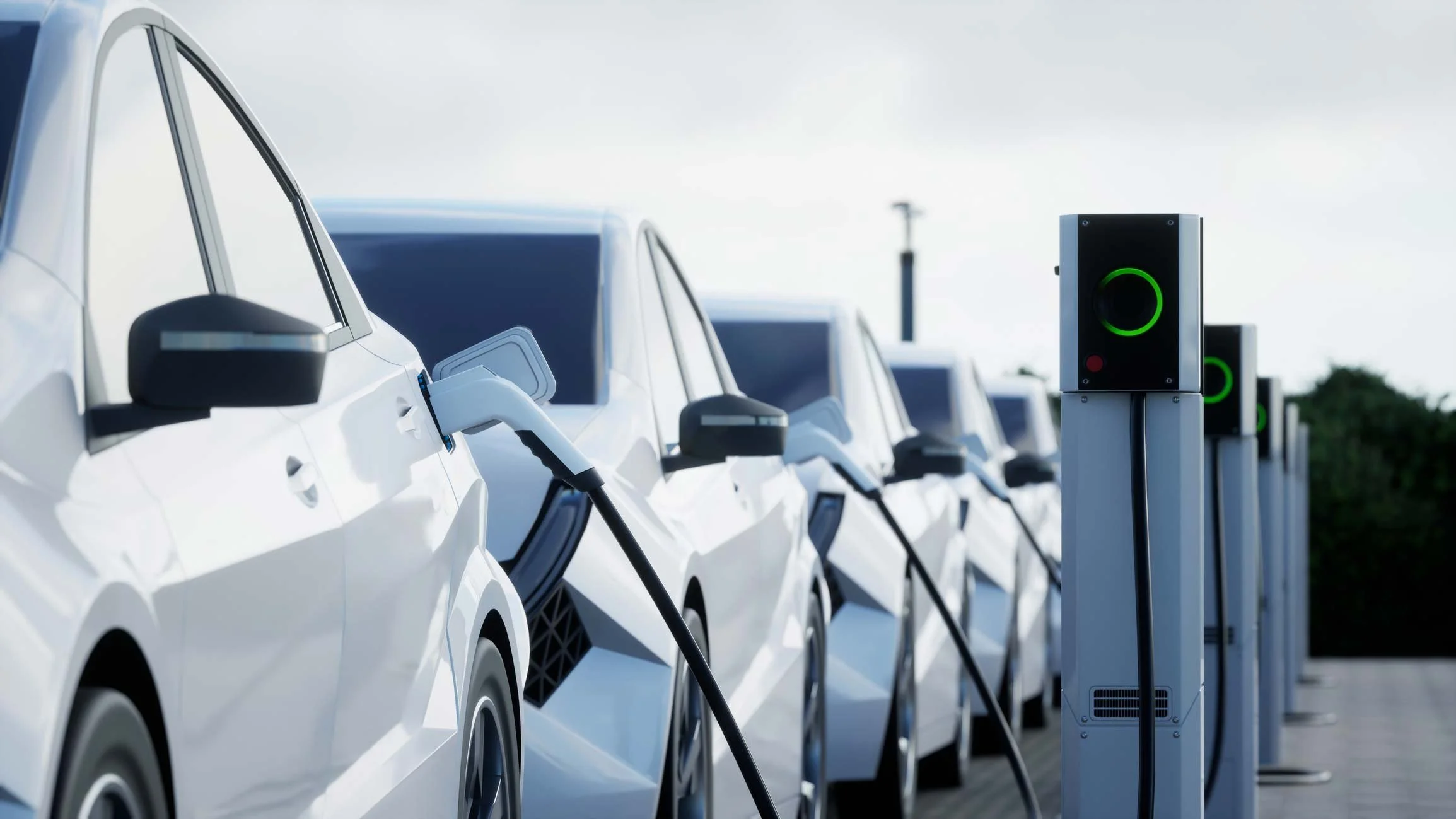 Several white electric cars charging at a charging station outdoors.